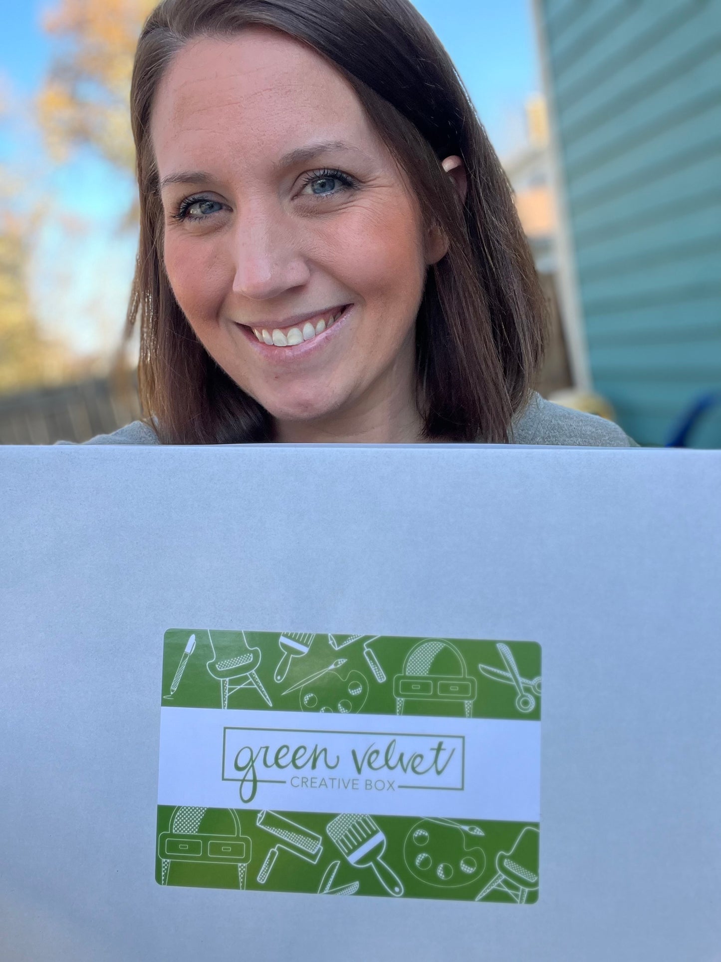 A person holding a Green Velvet Creative Box with a smile, indicating subscription box for craft and art supplies